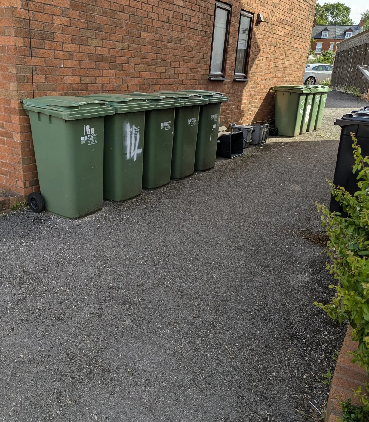 Stroud District Council green wheelie bins, the district's recycling bin, behind flats in Stonehouse